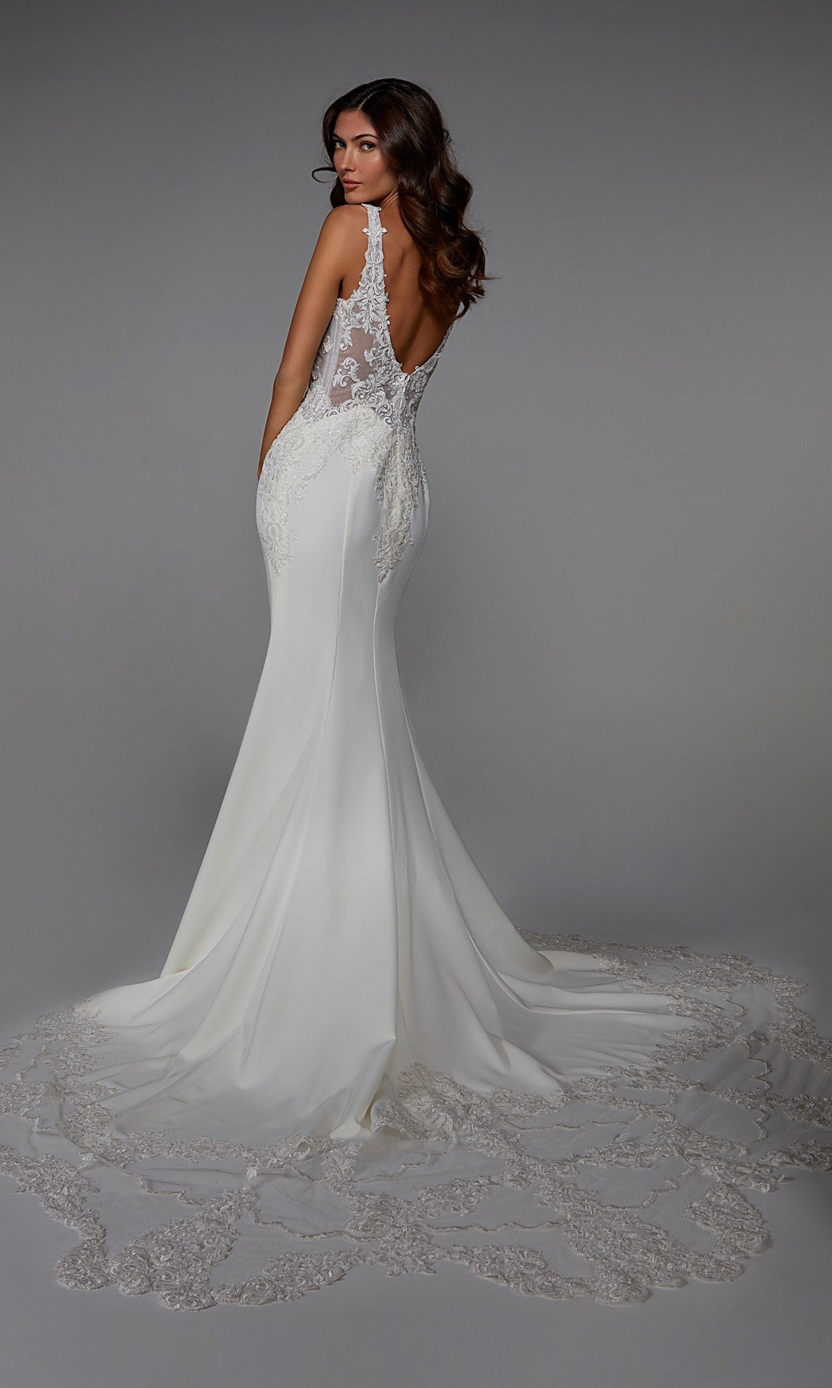 A woman faces away from the camera in the Alyce 7027 long white dress, featuring a backless design, sleeveless cut, lace embroidery, and a long train.